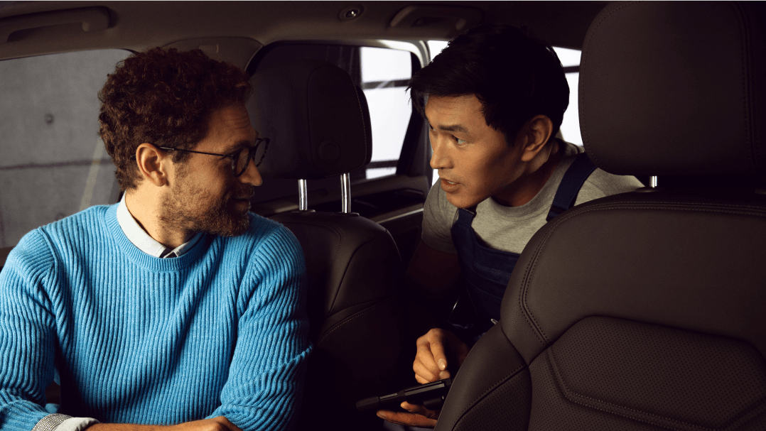 A customer dressed in blue consulting an authorised Volkswagen aftersales consultant on the leather condition of the Volkswagen vehicle.