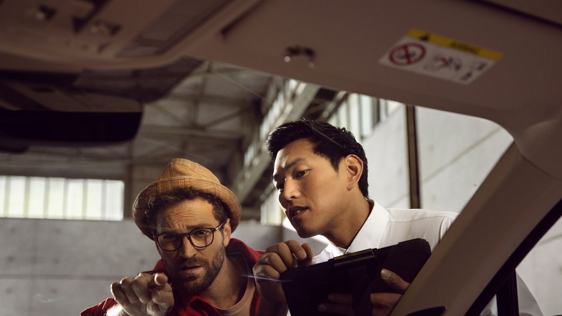 A customer directing the attention of an Authorised Volkswagen Aftersales consultant towards the interior of his Volkswagen vehicle in a service workshop.