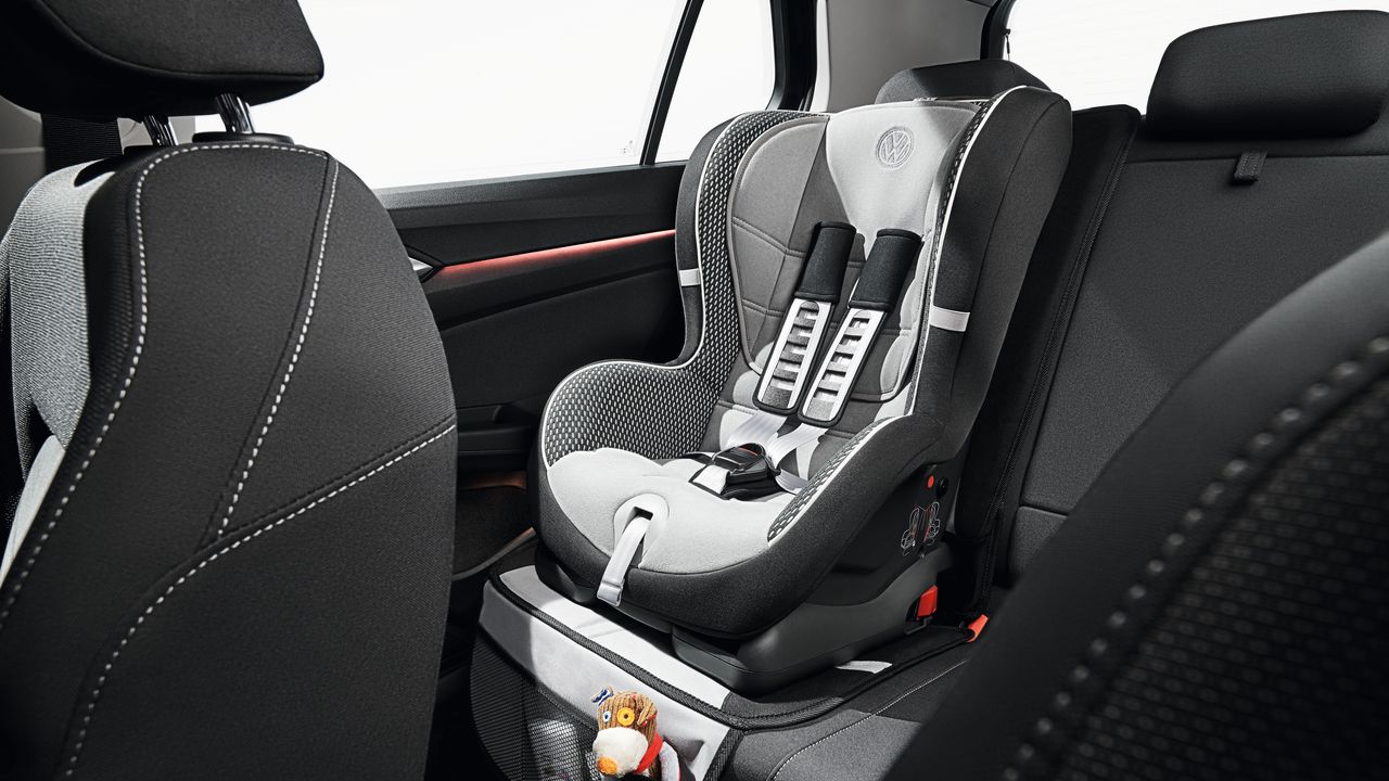 A vacant baby car seat being mounted on the right side of the backseat of a Volkswagen vehicle.