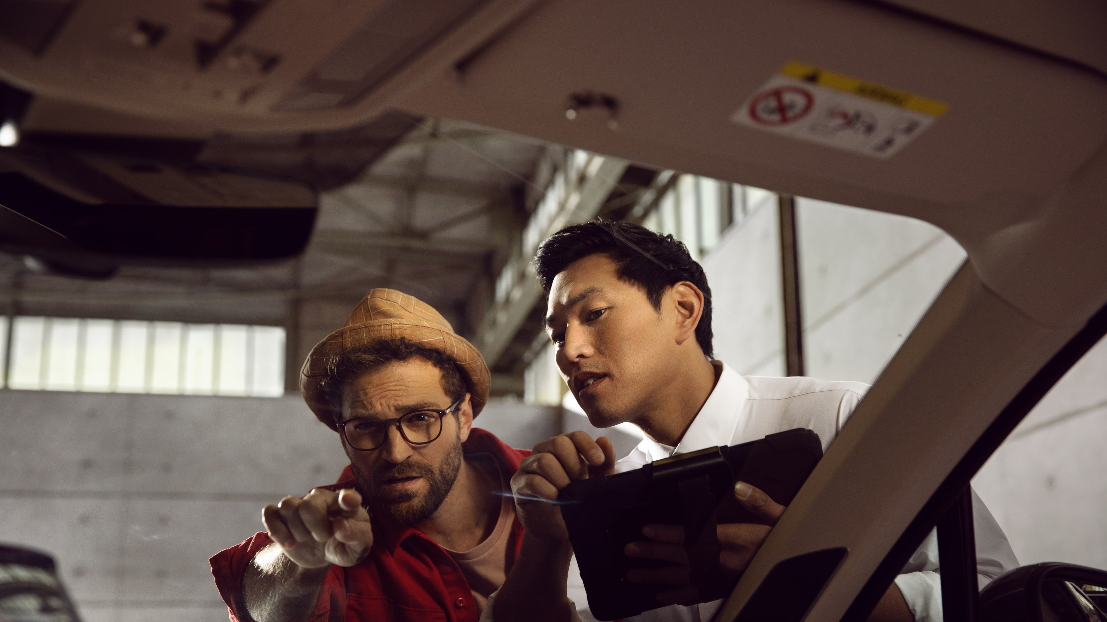 A customer directing the attention of an Authorised Volkswagen Aftersales consultant towards the interior of his Volkswagen vehicle in a service workshop.