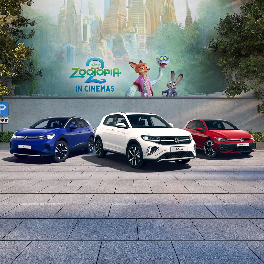 A blue ID.4, white T-Cross and red Golf GTI parked in front of a Zootopia 2 mural