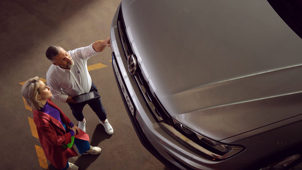 A female customer who owns a silver Volkswagen vehicle seeking a consultation with a Certified Volkswagen Staff with regards to the exterior condition her vehicle in a service workshop.