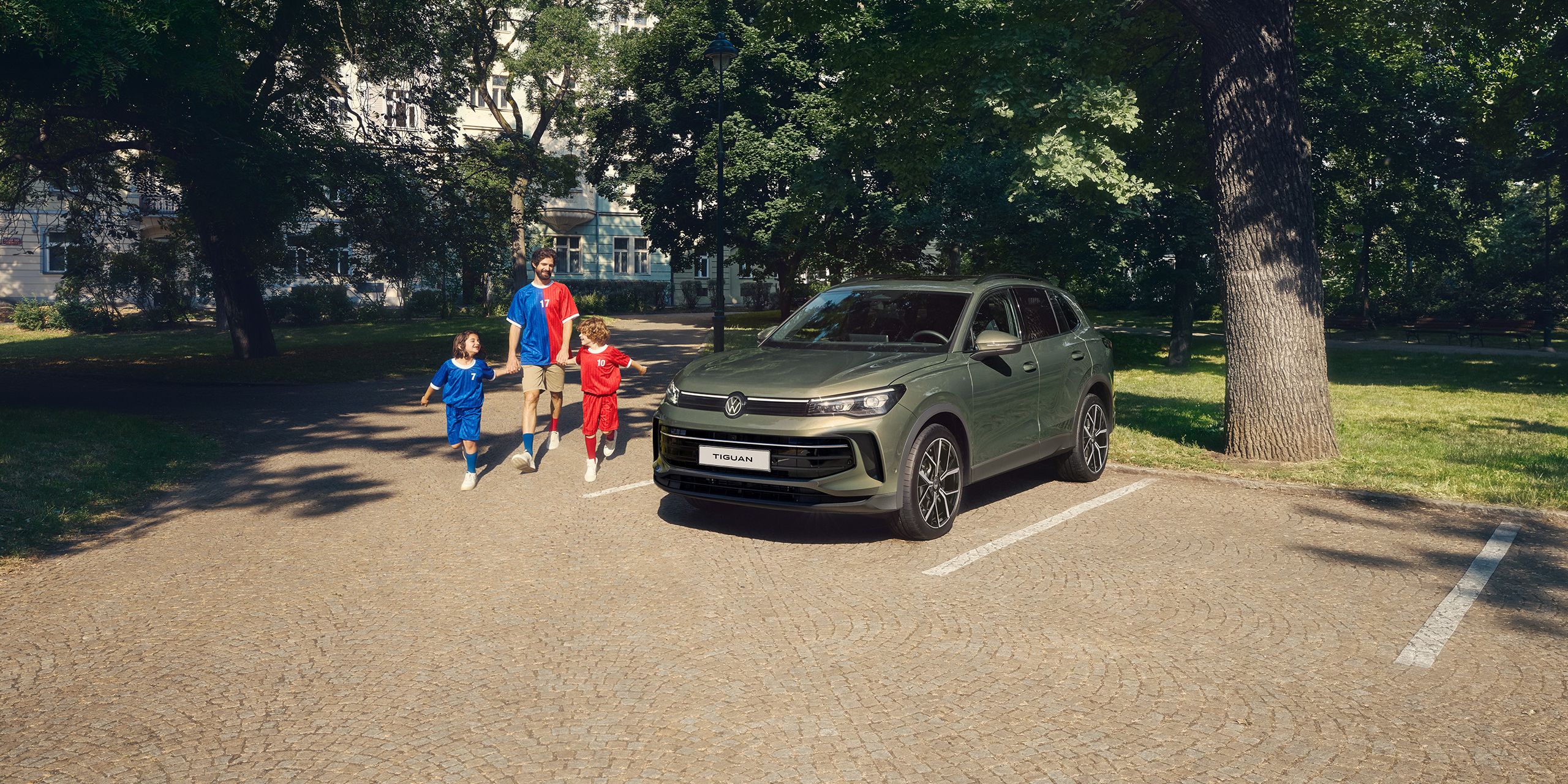 A family of three walking merrily by their trusty Tiguan