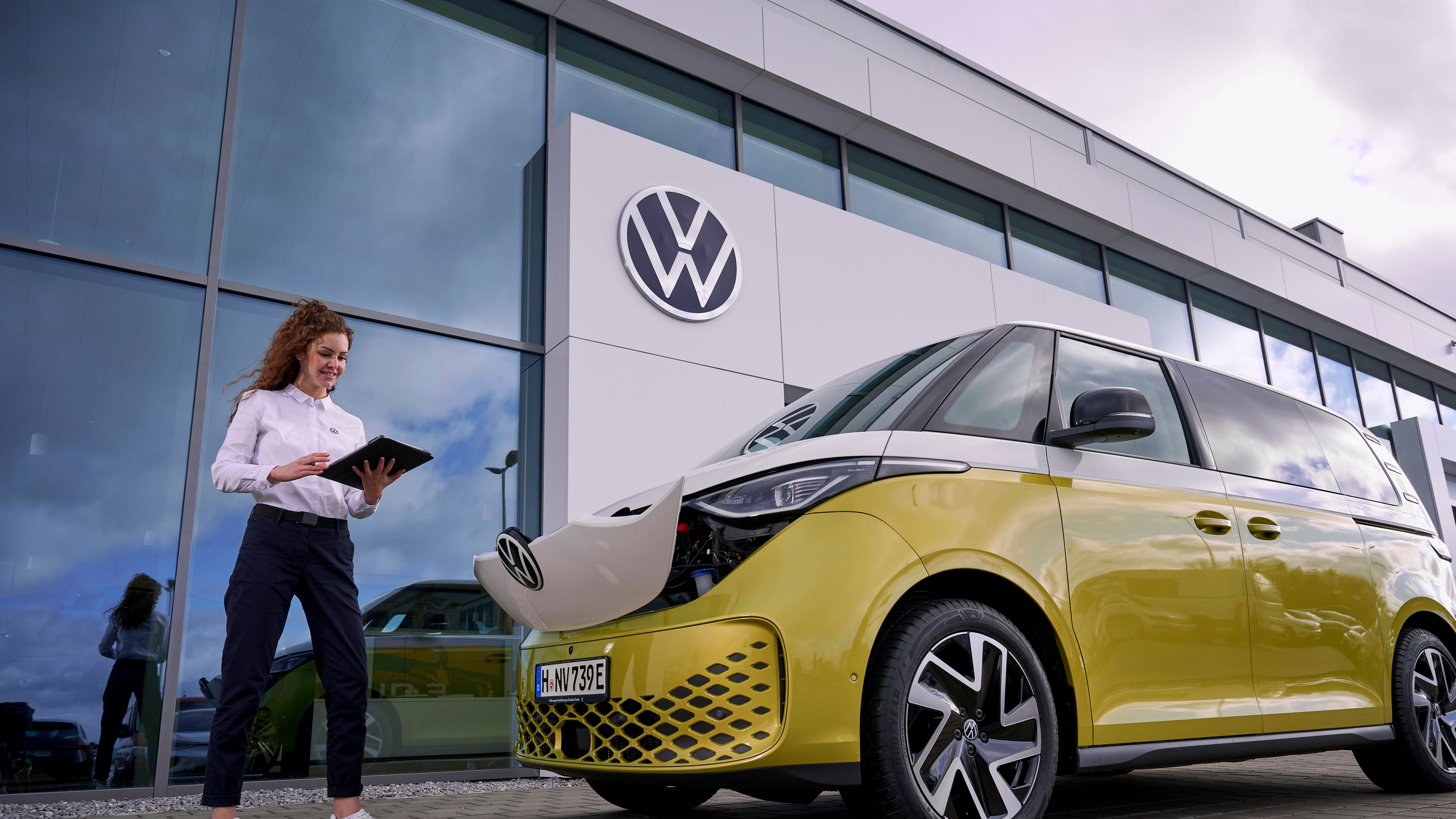 A Volkswagen technician checking on the ID. Buzz in Candy White Lime Yellow