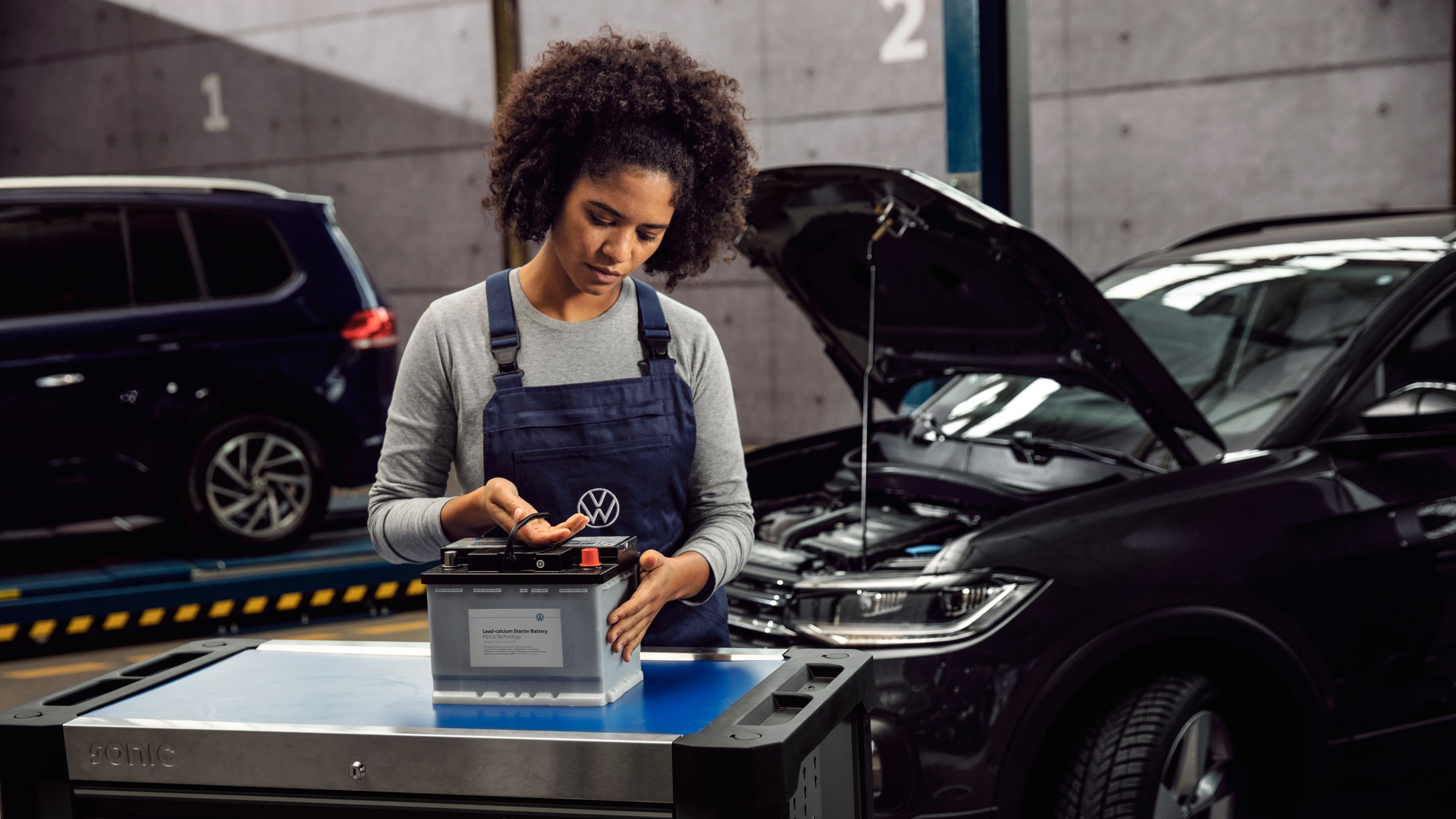 A Certified Volkswagen Staff assessing the condition of a Volkswagen Genuine Battery on a work station at the service centre.