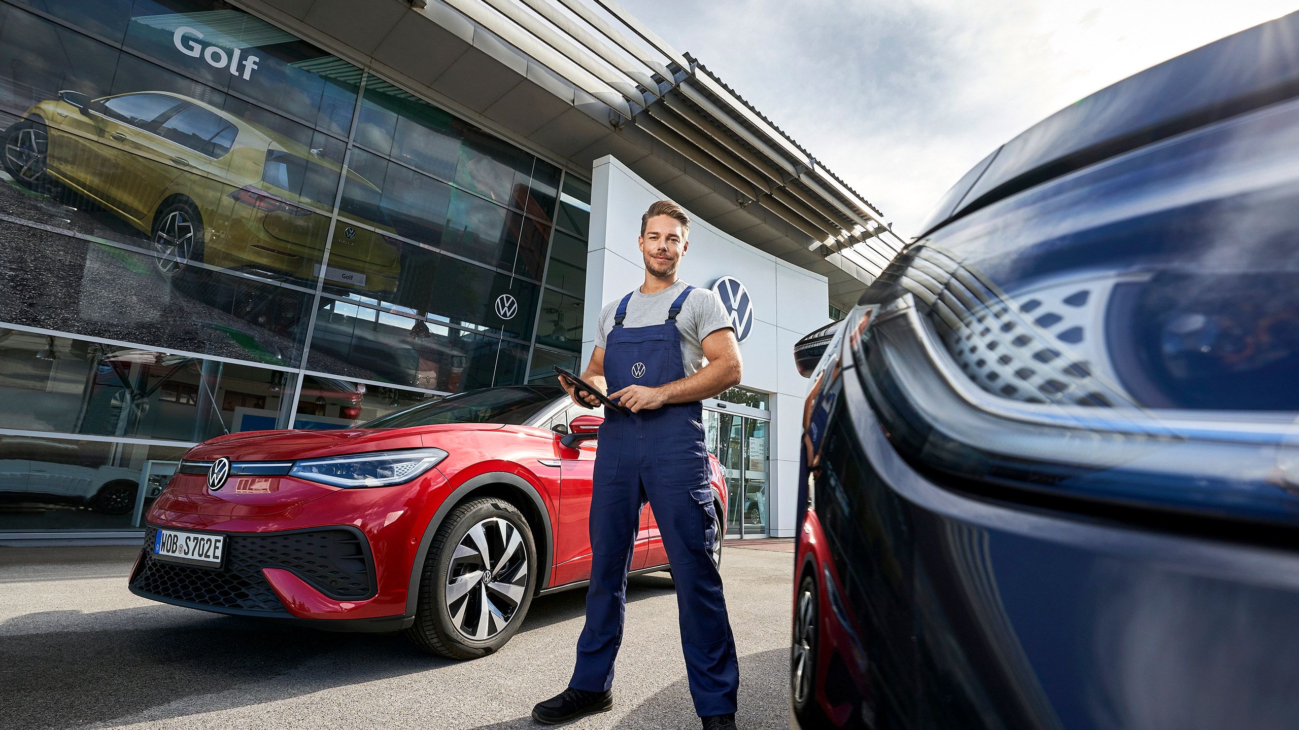 A Volkswagen service advisor holding an iPad and standing between ID.5 at the service center