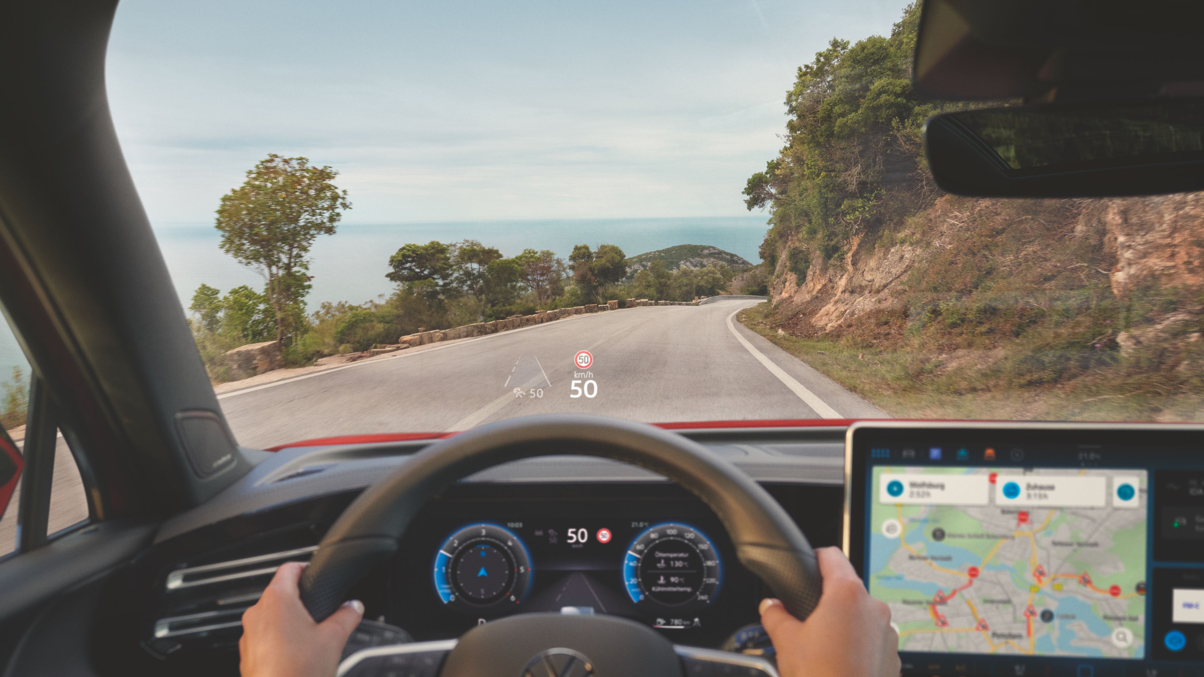 An image depicting a person driving in a Volkswagen vehicle on an open road with its navigation system turned on.