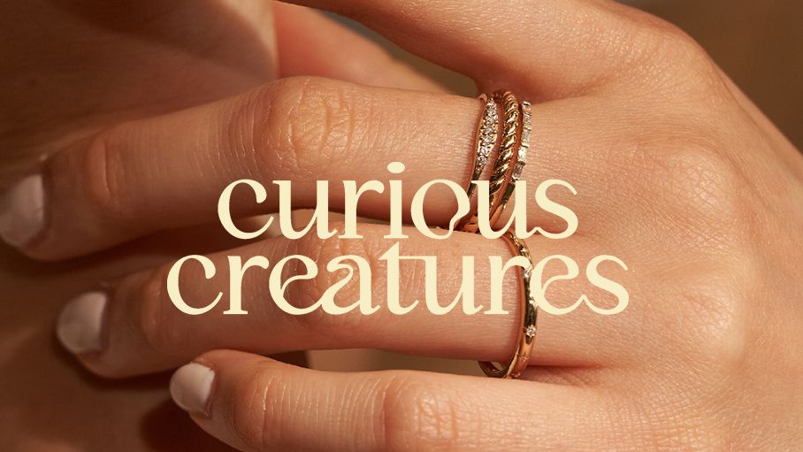 Hand with rings with curious creatures logo