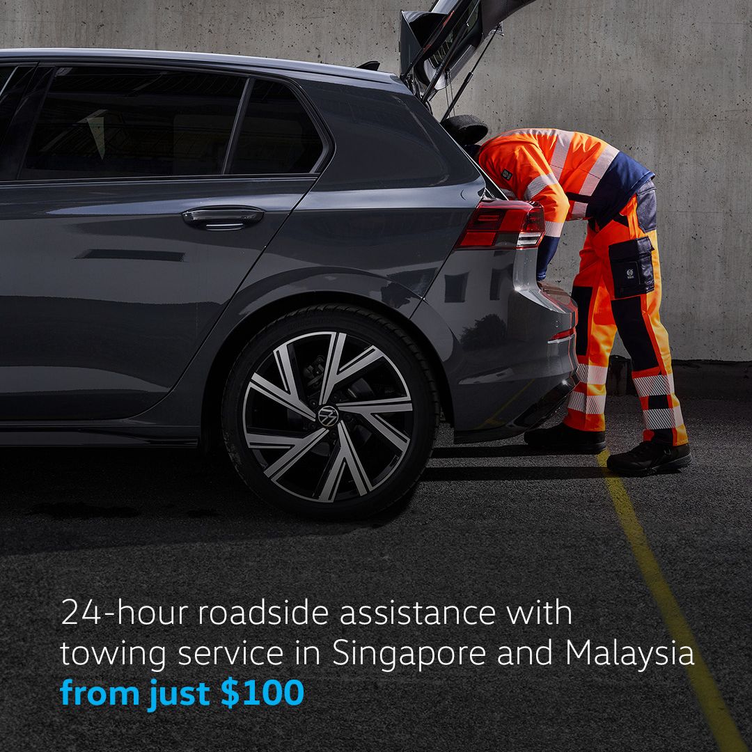 A trusted repairman providing Roadside Assistance to a parked Volkswagen.