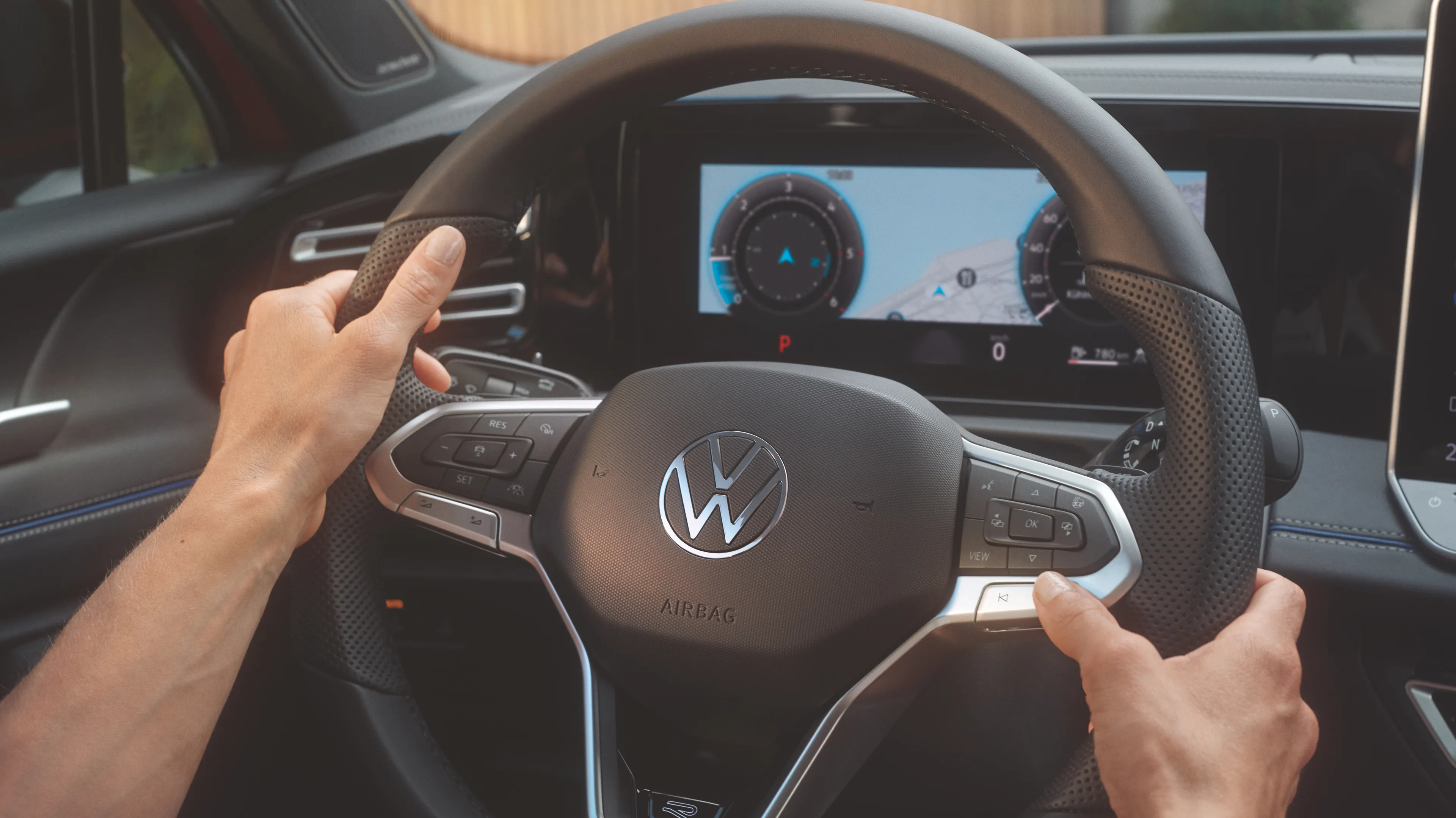 A close up shot of a person handling the multi-function steering wheel of a Volkswagen Tiguan.