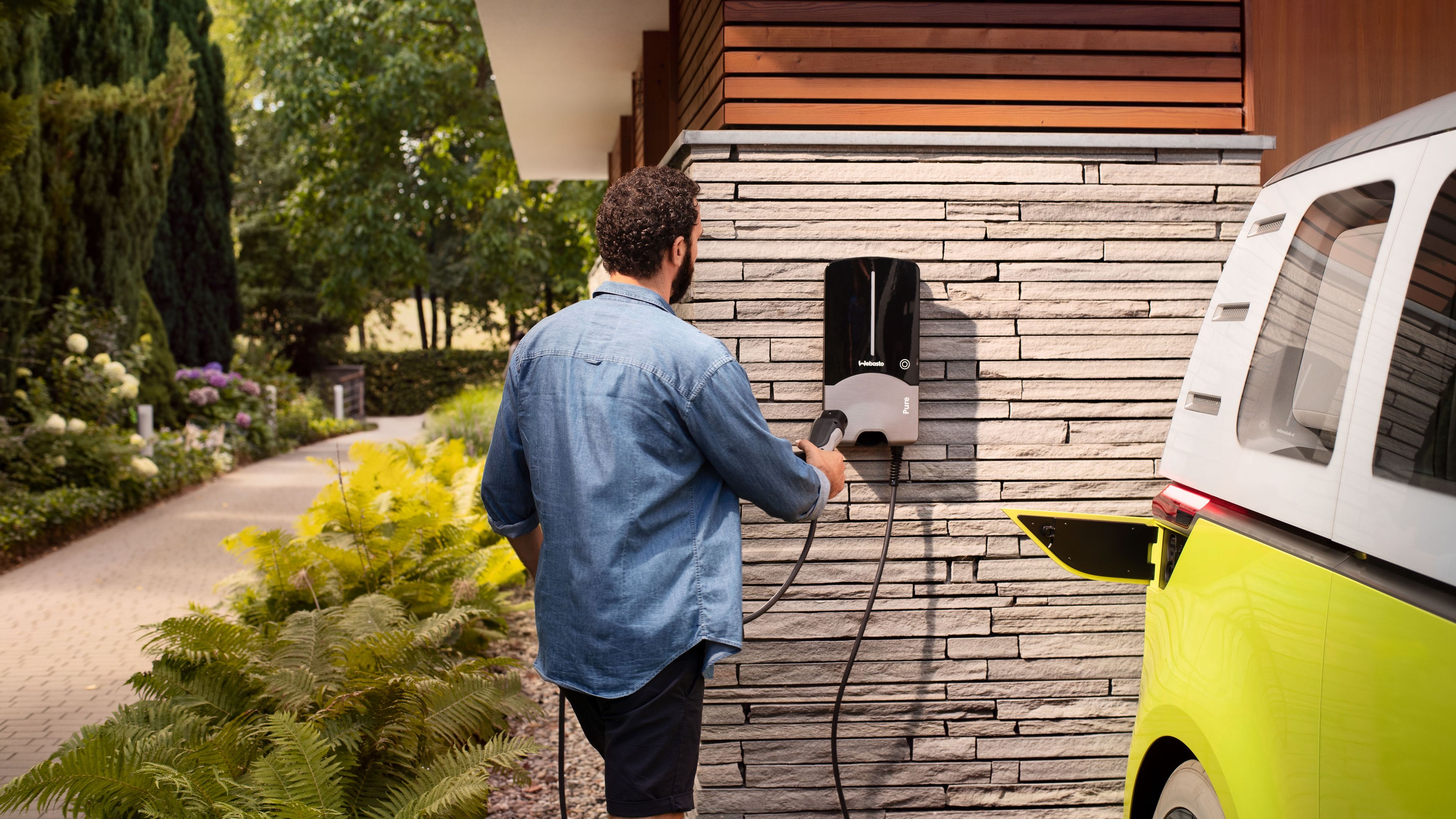 A man is holding the charger on the wall beside the yellow ID.Buzz