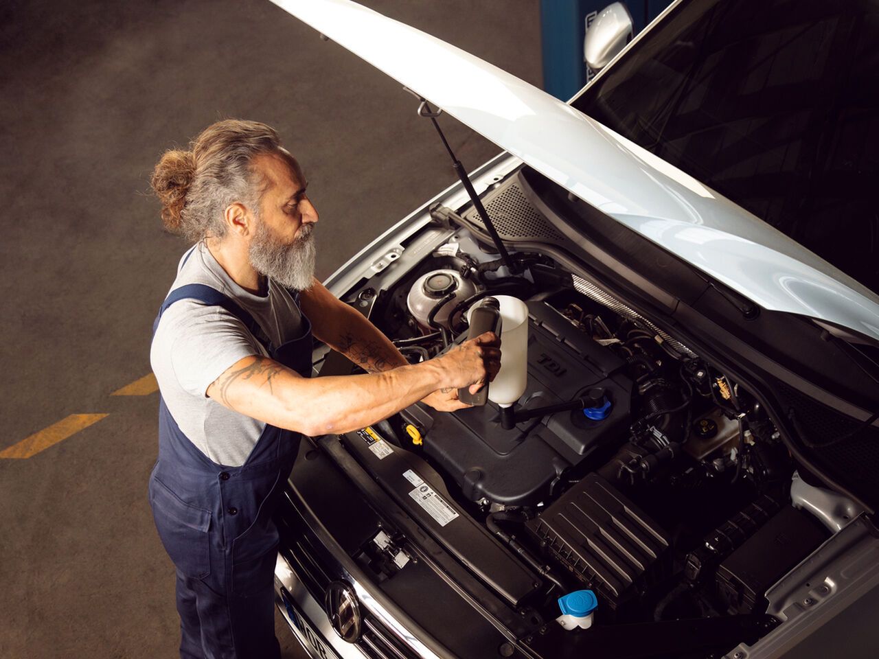 A Volkswagen technician is seen inspecting the engine of a Volkswagen vehicle to ensure all processes are undergoing smoothly.