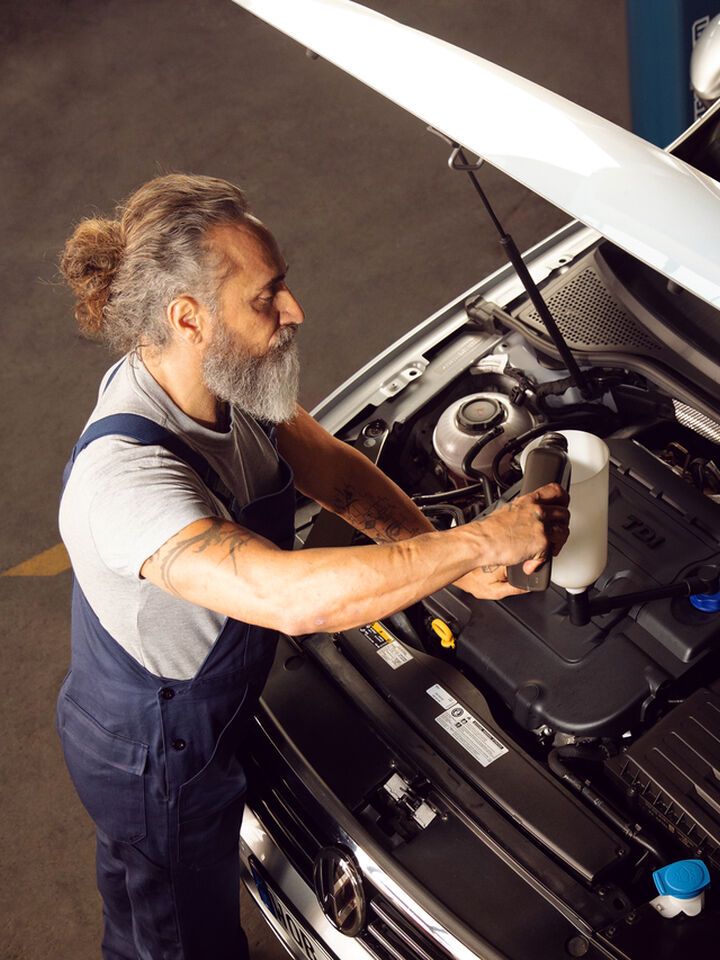 A Volkswagen technician is seen inspecting the engine of a Volkswagen vehicle to ensure all processes are undergoing smoothly.