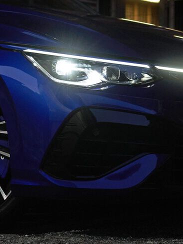 A blue Volkswagen vehicle with the 'Estoril' alloy wheels and LED headlamp is turn on
