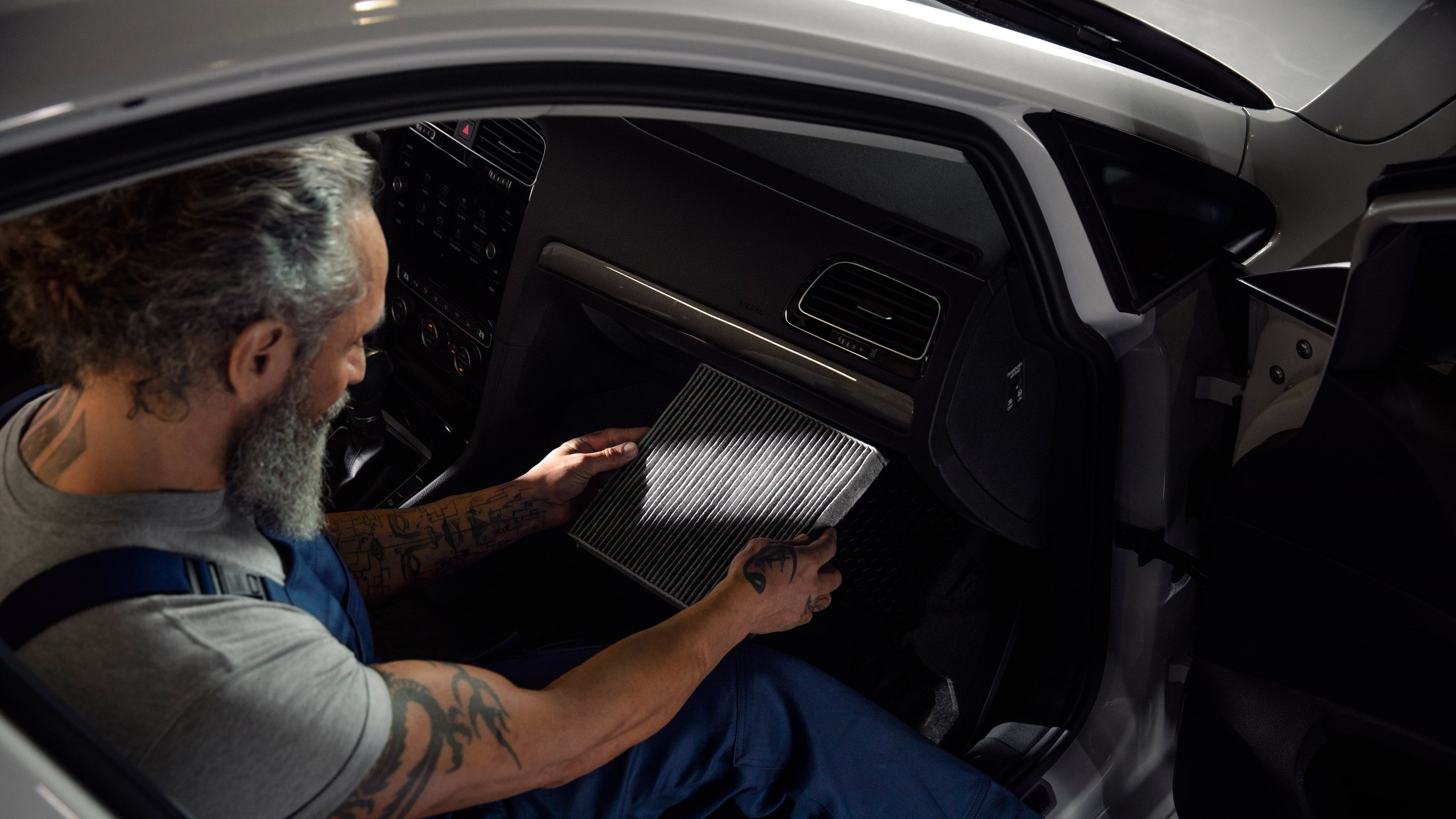 A Certified Volkswagen Staff expertly checks the condition of the air filters in a Volkswagen vehicle.