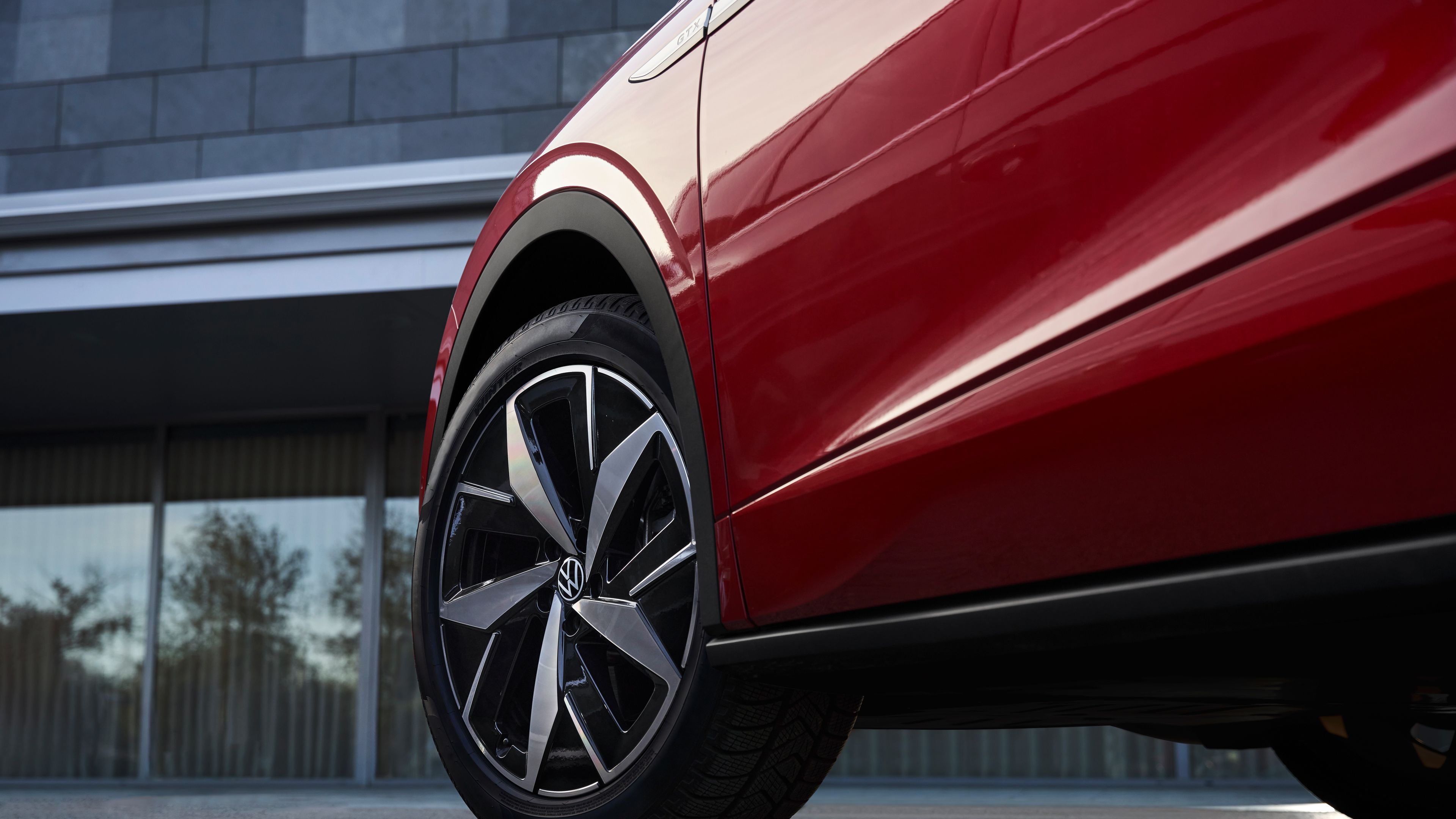 A Kings Red Volkswagen ID.5 GTX with the 'Ystad' rims parking infront modern building