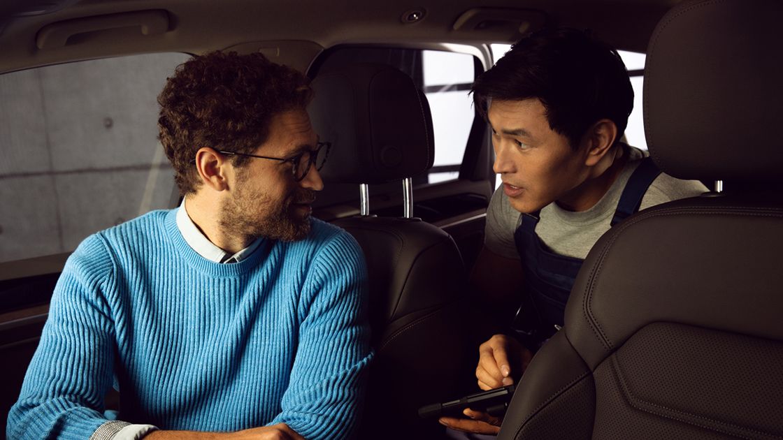A customer dressed in blue consulting an authorised Volkswagen aftersales consultant on the leather condition of the Volkswagen vehicle.