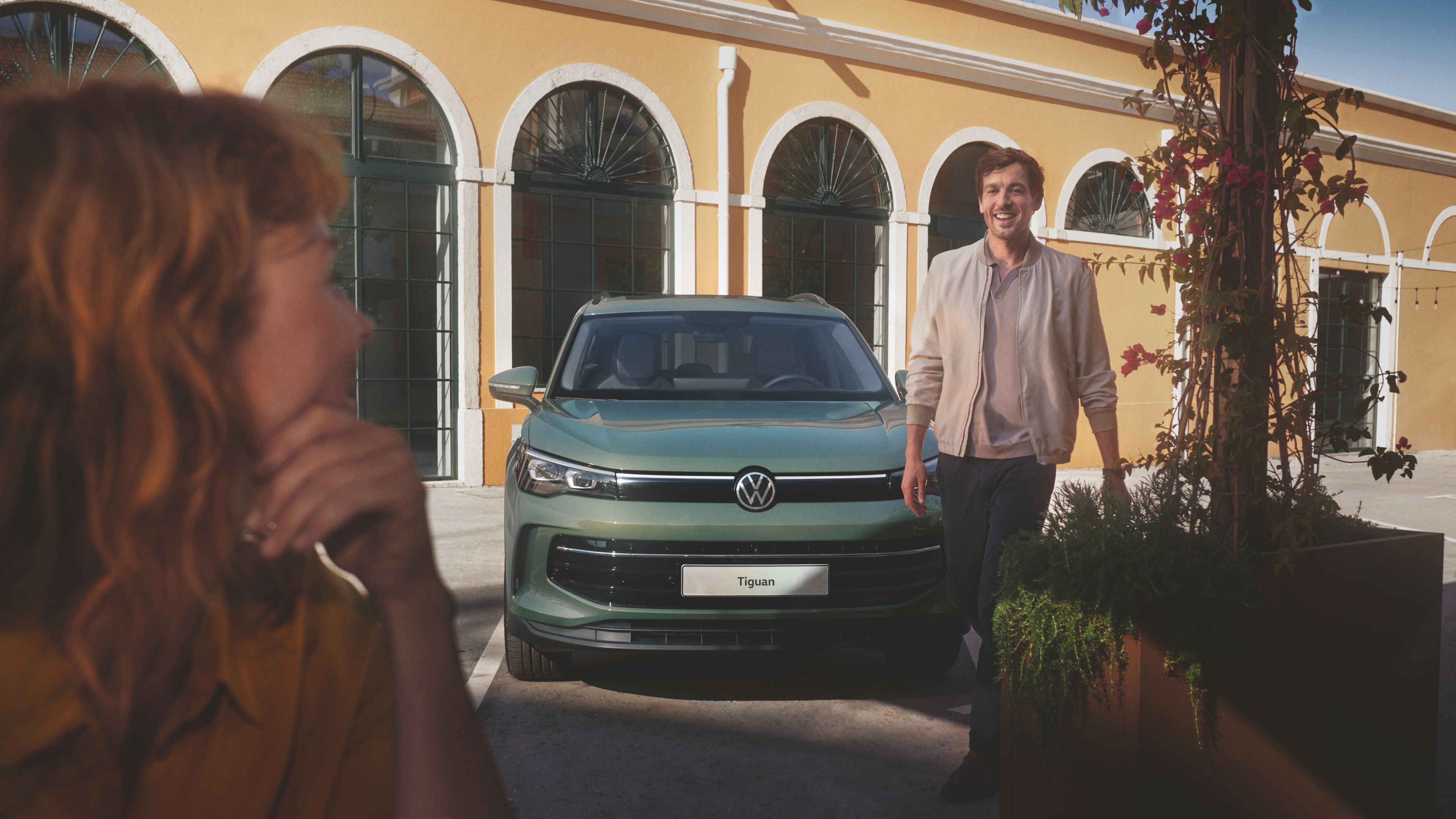 Man walking in front of new Tiguan model in Cipressino Green Metallic.